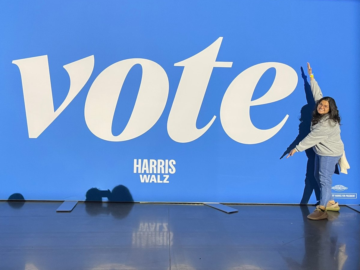 Stephanie Mendoza in front of a large VOTE mural
